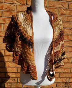 a white mannequin wearing a brown crocheted jacket on top of a brick wall