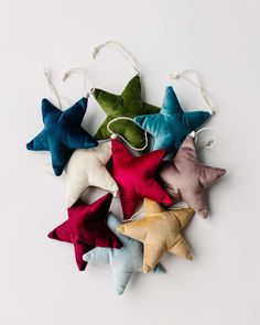 six star ornaments in various colors and sizes on a white background, with string hanging from the top