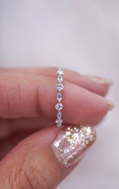 a woman's hand holding a diamond ring in her left hand, with diamonds on it