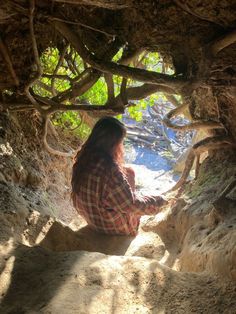 a woman sitting in the middle of a tunnel with trees growing out of her back