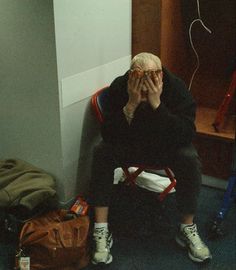 a man sitting in a chair covering his eyes