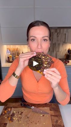 a woman is eating a chocolate donut with sprinkles