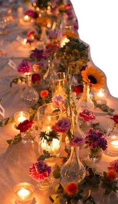 a long table with candles and vases filled with flowers on top of each other