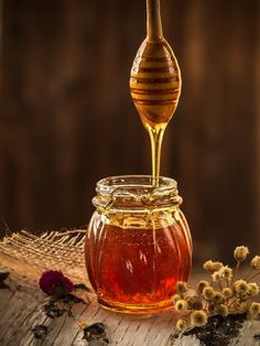 a glass jar filled with honey sitting on top of a wooden table