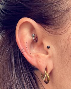 a close up of a person's ear with two piercings on top of it