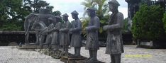 a row of statues sitting on top of a stone walkway