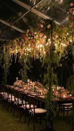 a long table with flowers and greenery hanging from the ceiling