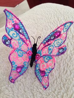 a pink and blue butterfly sitting on top of a bed