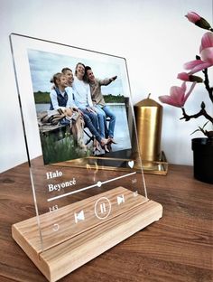 a wooden stand with an mp3 player on it next to a vase and pink flowers