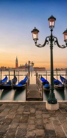 several gondolas are lined up on the dock in front of a light pole