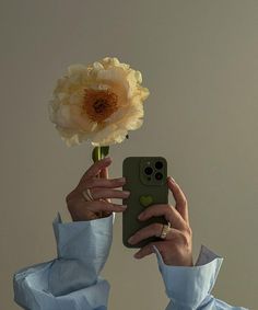 a woman taking a selfie with her cell phone while holding a flower in front of her face