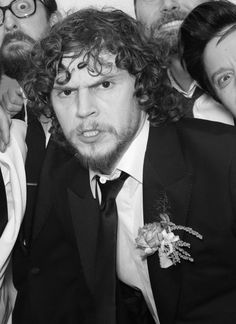 a group of men in suits and ties posing for a photo with one man's face covered by curly hair