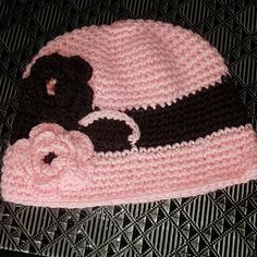 a pink and black crocheted hat with a teddy bear on it's side