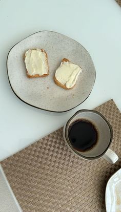 two pieces of bread on a plate next to a cup of coffee