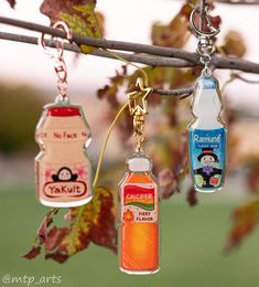 three bottle shaped key chains hanging from a tree branch