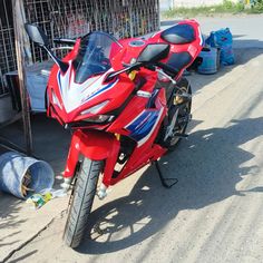 a red and white motorcycle parked next to a metal cage on the side of a road