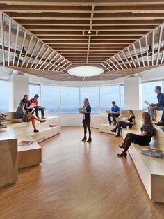 people are sitting on benches in the middle of a room with large windows overlooking the ocean