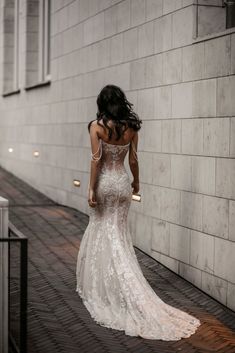 a woman in a wedding dress is walking down the street with her back to the camera