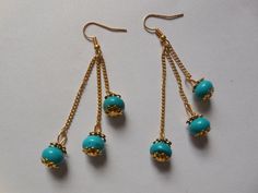 three pairs of gold and turquoise beaded earrings on a white surface with chain links