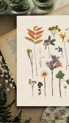 an open book sitting on top of a table next to flowers and plants in vases