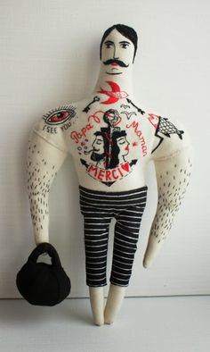 a stuffed doll with tattoos on it's chest holding a black bag and wearing striped pants