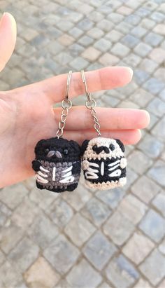 two black and white crocheted keychains in the palm of someone's hand