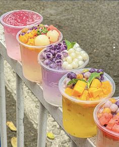 four plastic cups filled with different types of fruit and veggies on a ledge