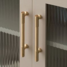 two brass handles on a white door with black and silver striped curtains in the background