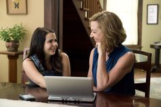 two women sitting at a table with a laptop