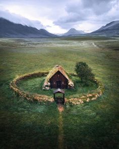 an aerial view of a house in the middle of a field with mountains in the background