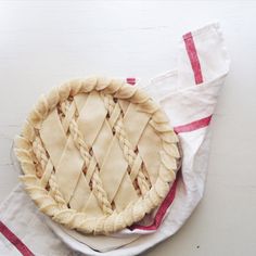 an uncooked pie sitting on top of a white plate next to a red and white towel