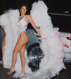 a woman standing next to a white car