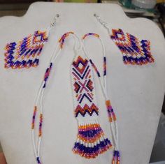 This Beautiful Native American Beaded Necklace and Earring Set is made by Elaine out of White, Orange, Hot Pink and Dark Purple Delica Beads. Multicolor Southwestern Beaded Necklace With Dangling Beads, Southwestern Beaded Necklace With Dangling Beads For Festivals, Southwestern Style Festival Beads With Dangling Details, Southwestern Style White Beaded Necklace With Large Beads, Southwestern Style Large White Beads, Southwestern Style White Jewelry With Dangling Beads, Southwestern Style White Beaded Necklace As Gift, White Southwestern Style Beaded Necklaces For Festival, Handmade White Beaded Southwestern Necklace