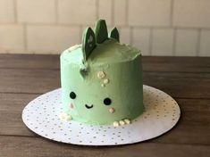 a green cake sitting on top of a wooden table next to a white polka dot plate