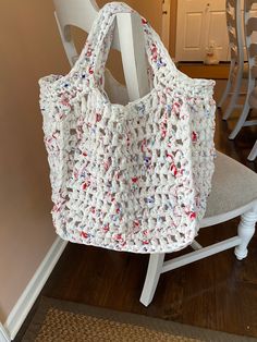 a crocheted bag sitting on top of a white chair next to a wooden floor