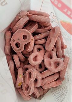 pink donuts with holes in them sitting on top of a paper bag filled with doughnuts