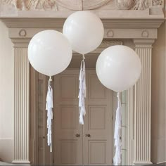 three white balloons hanging from the ceiling in front of a doorway with statues on either side