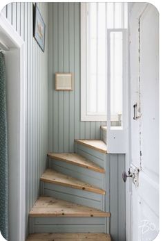 a set of wooden stairs leading up to a window in a room with green walls