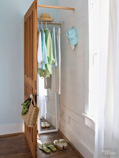 an open closet with shoes and clothes hanging on the door, in front of a window