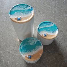 three cups with blue and white designs on them sitting on the floor next to each other