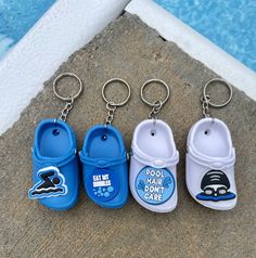 three pairs of blue and white sandals keychains next to a pool with water