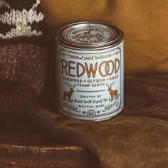 a can of red wood sitting on top of a brown couch next to a knitted hat