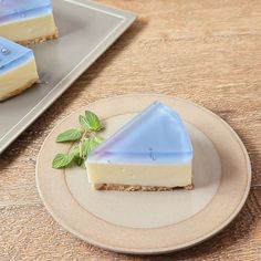 two slices of cheesecake on a plate next to a slice of mint sprig