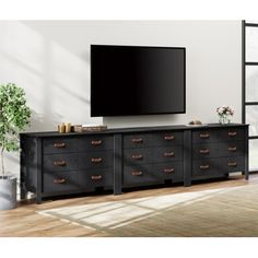 a large flat screen tv mounted to the side of a black dresser in a living room