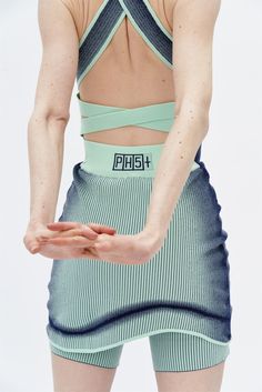 a woman with her hands out in front of her back, wearing shorts and a crop top