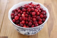 a bowl filled with cranberries sitting on top of a wooden table