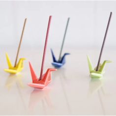 four small origami birds sitting on top of a white table next to each other