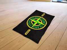 a black mat with a yellow and green logo on it sitting on a wooden floor