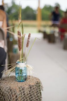 a mason jar filled with water and reeds sitting on top of a burlock