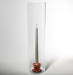 a tall candle is in a glass vase